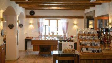 A rustic interior with wooden beams, a buffet table with food items, and a display of jars.
