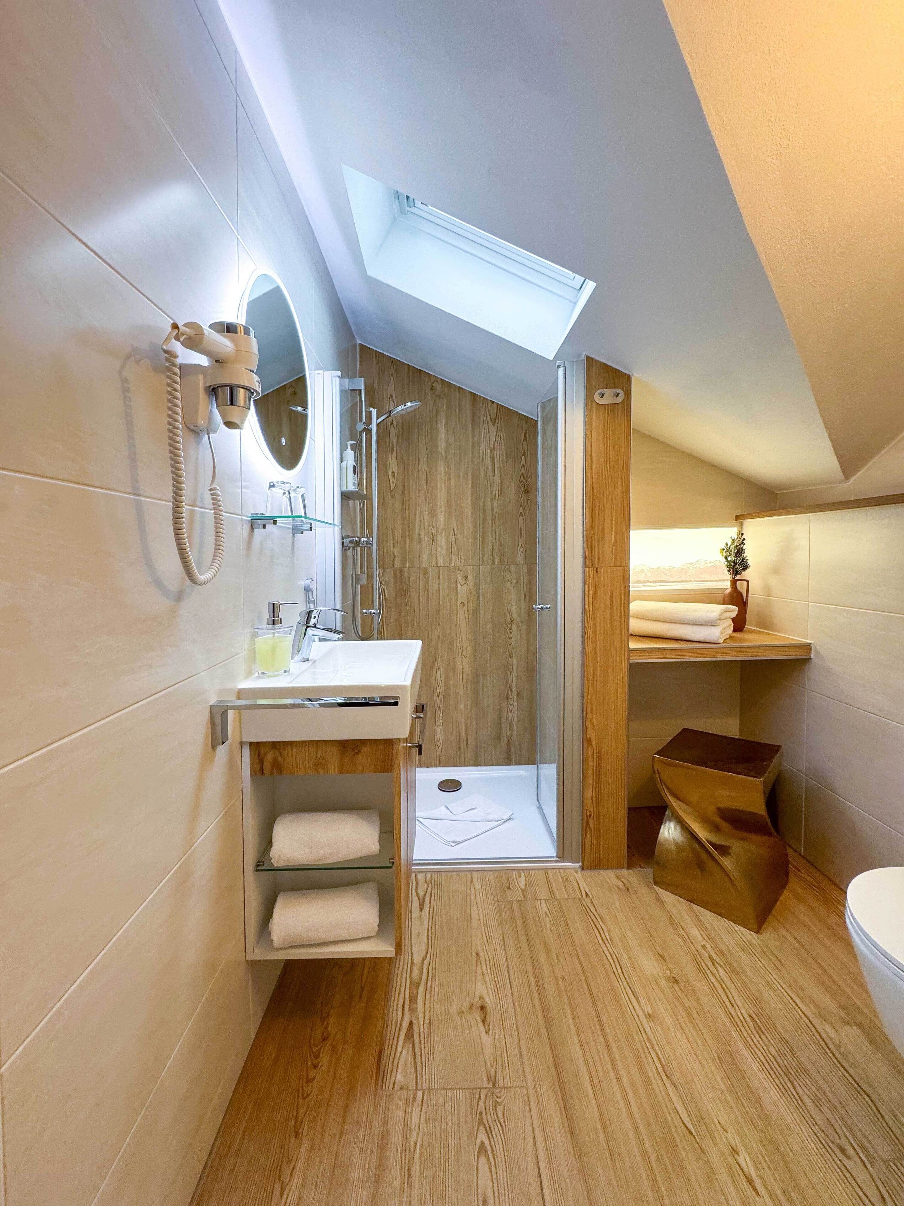 Un baño moderno con tragaluz, tocador de madera y ducha.
