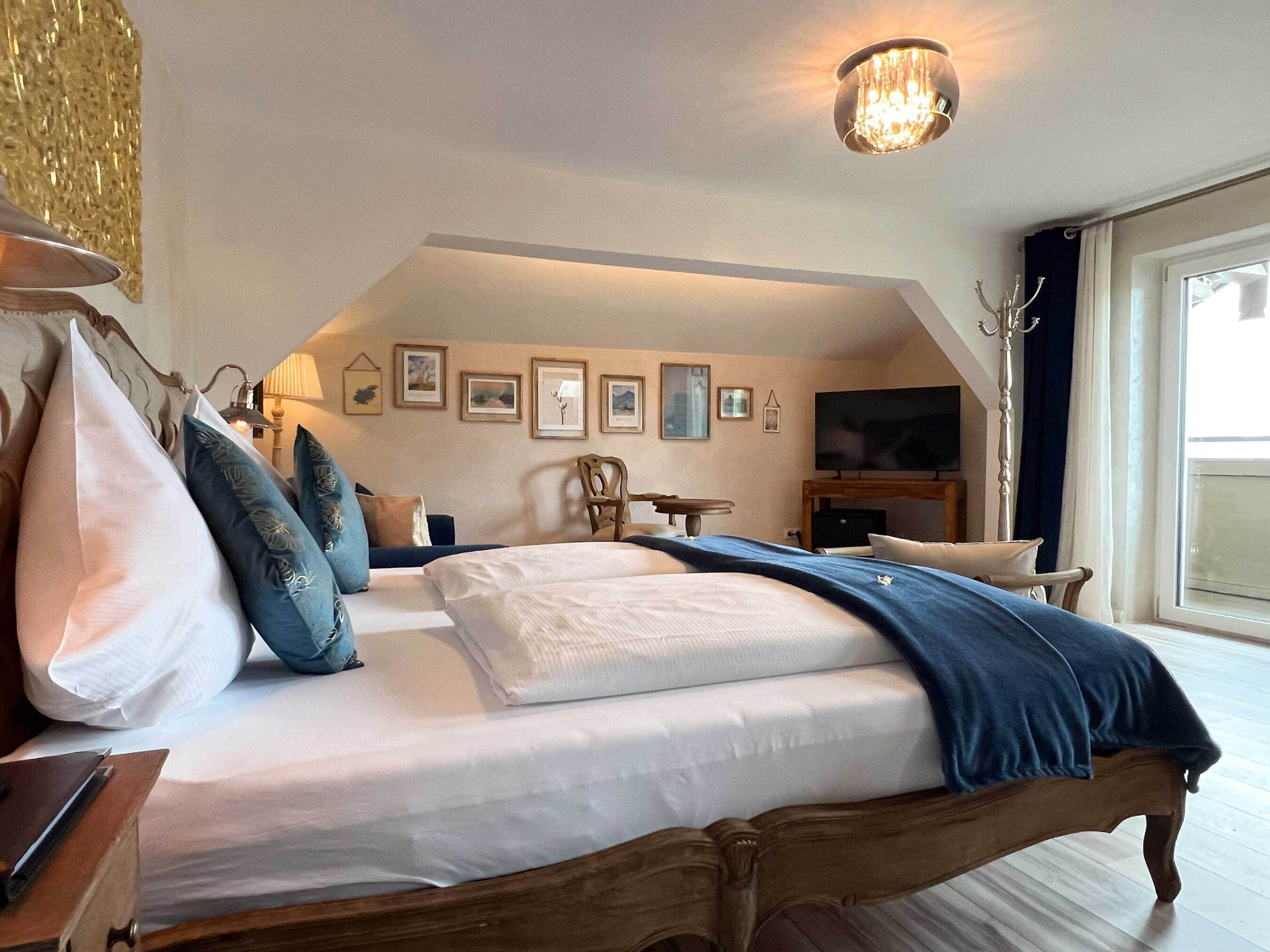 A bedroom with a large bed, a TV, and framed pictures on the wall.