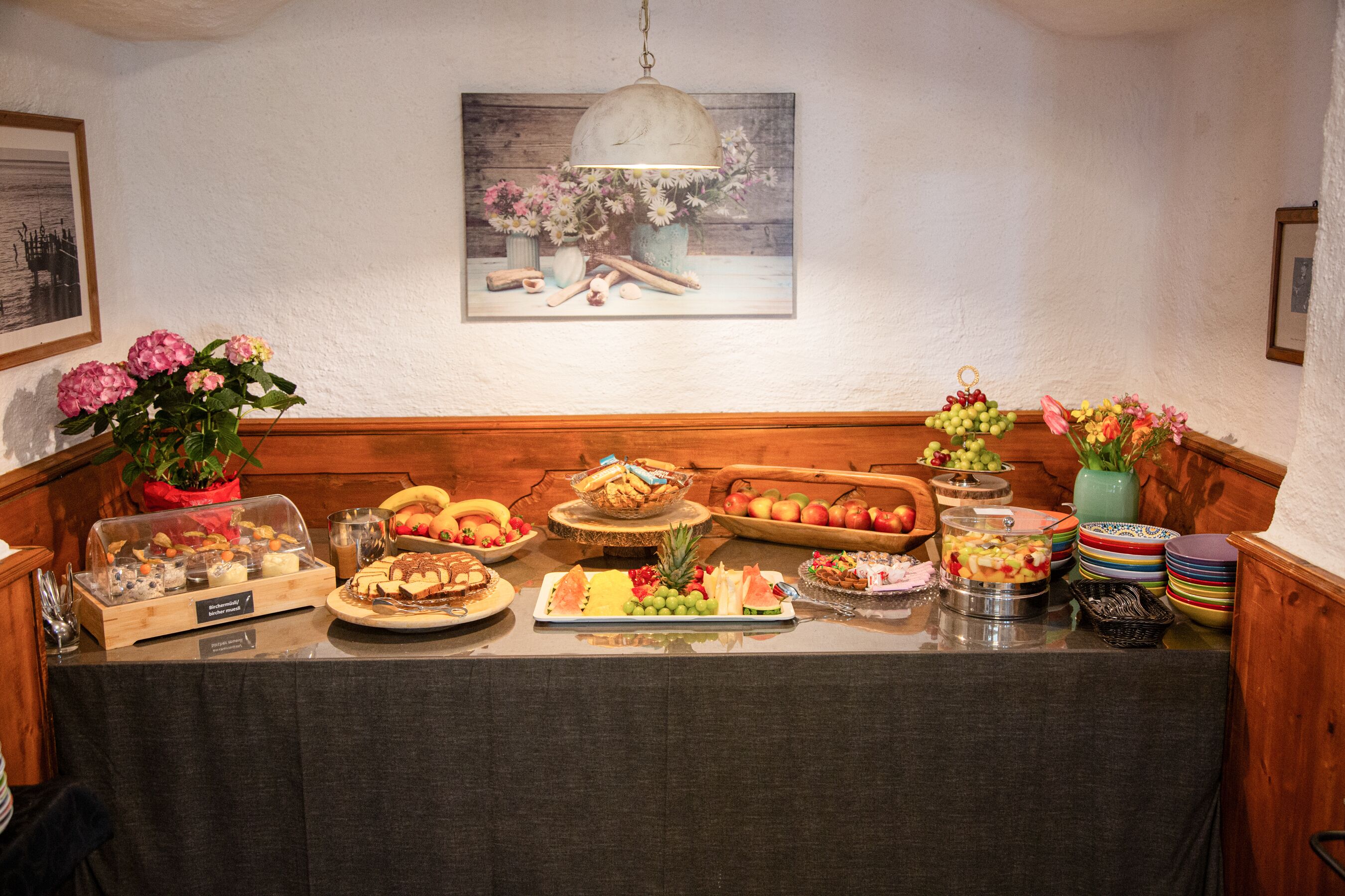A buffet table with various food items and a painting on the wall.