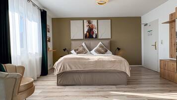 A bedroom with a large bed, a chair, a wooden floor, and a ceiling light fixture.
