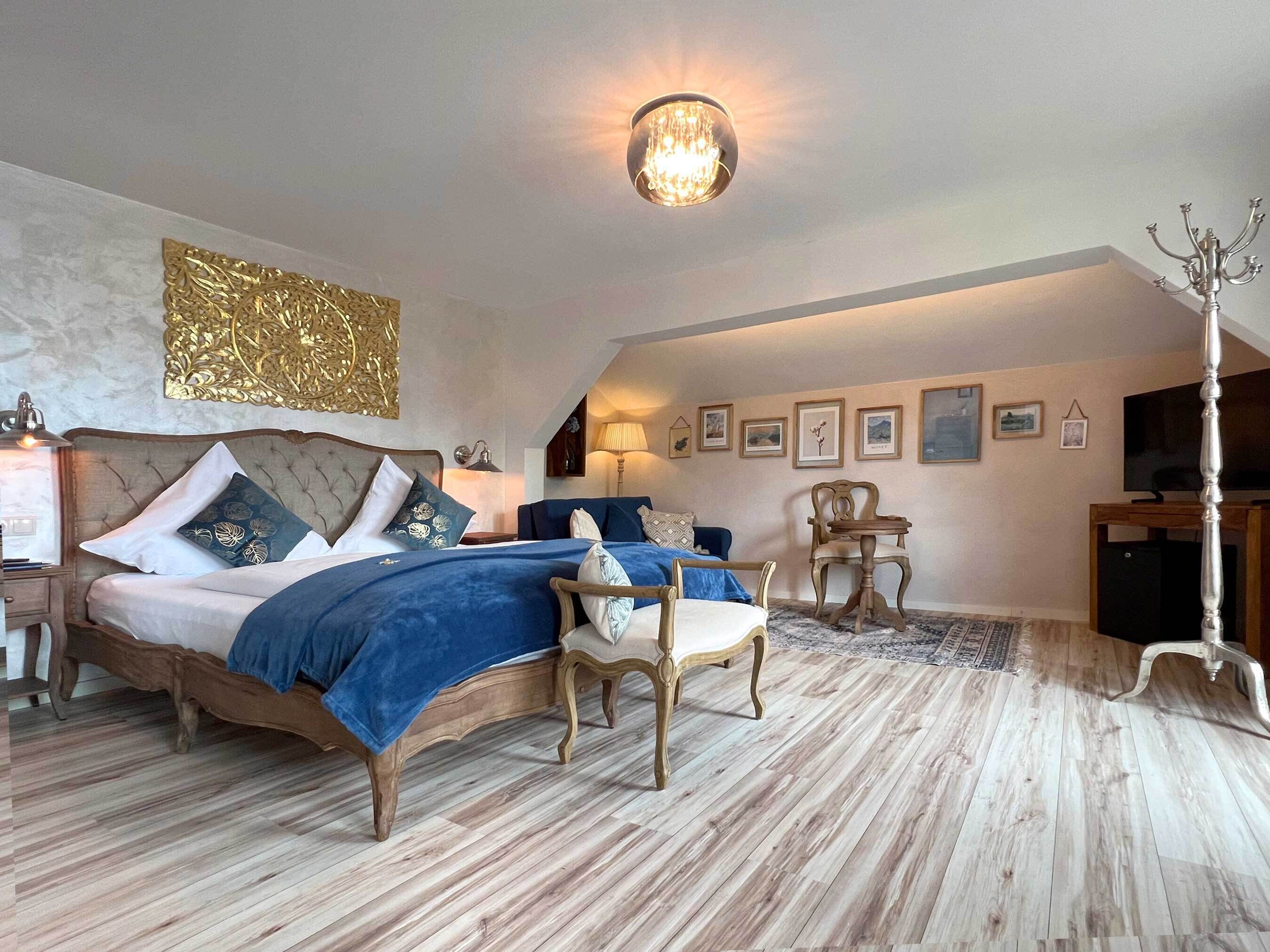 Ein Schlafzimmer mit einem großen Bett, einem Sessel, einem Tisch und einem Fernseher.