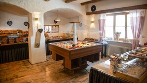 A buffet setup with a variety of food items, wooden beams on the ceiling, and a window with curtains. - Gästehaus Sieben Zimmer am See  (Prien am Chiemsee)