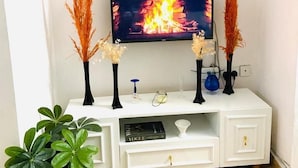 A living room with a TV, decorative plates, and a potted plant. - Lux Suites Bamburi Cozy Apartments (Mombasa)
