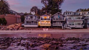 A beachfront property with multiple levels, a staircase leading to the beach, and a view of the ocean. - The Cottage at Miramar (Montecito)