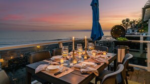 A table set for dinner with candles, overlooking the ocean at sunset. - The Cottage at Miramar (Montecito)