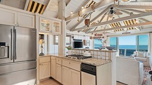 A spacious kitchen with a large island, stainless steel appliances, and a view to the sea. - The Cottage at Miramar (Montecito)