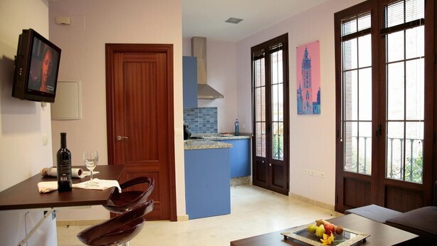 Una cocina moderna con una isla azul, un área de comedor con mesa y sillas, y un ventanal con vistas.
