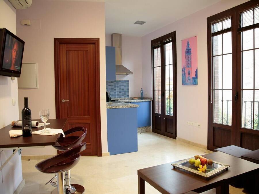 Una cocina moderna con una isla azul, un área de comedor con mesa y sillas, y un ventanal con vistas.