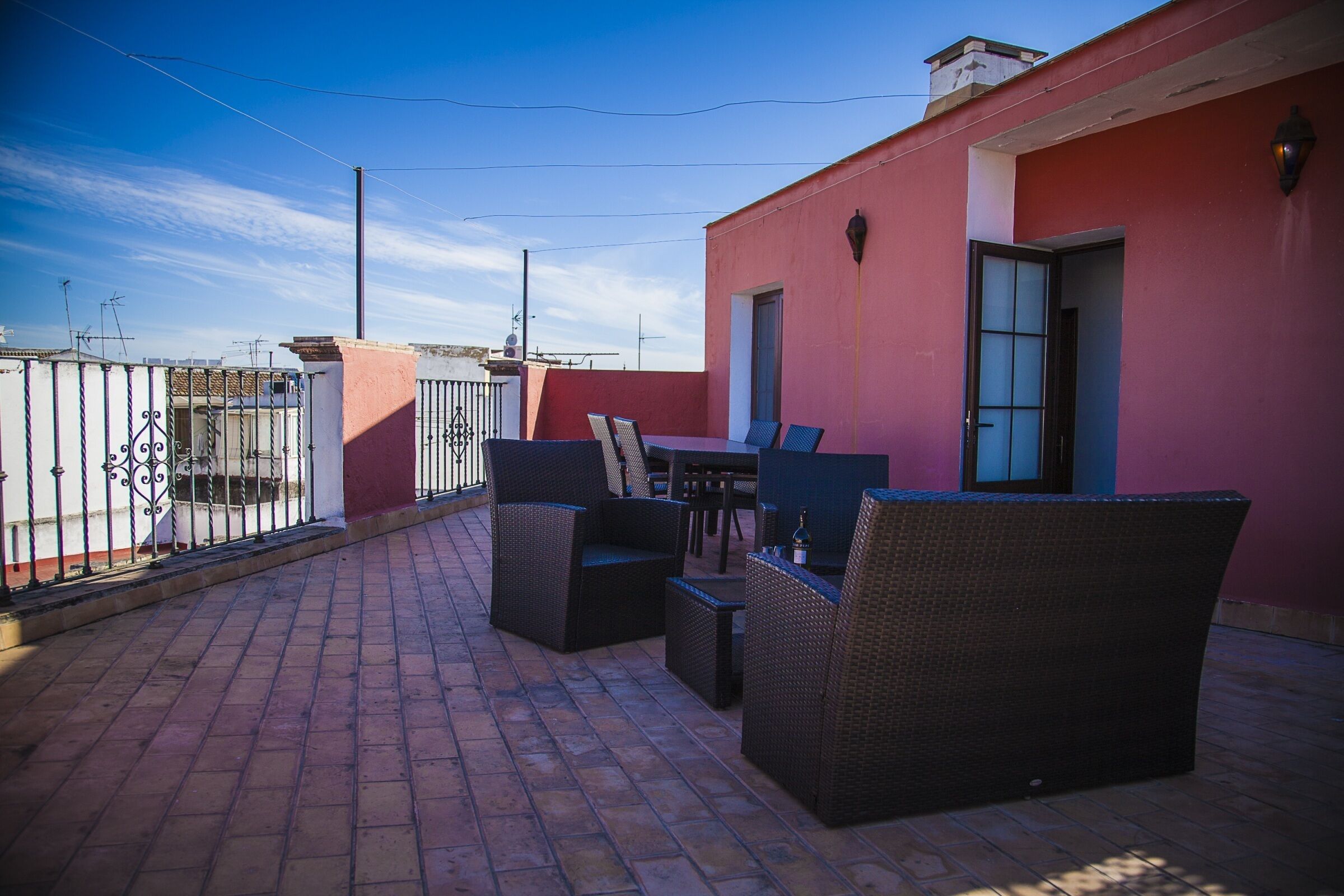 A rooftop patio with wicker furniture, a table, and a chair.