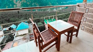 Ein Balkon mit Tisch und Stühlen mit Blick auf eine gebirgige Landschaft.
