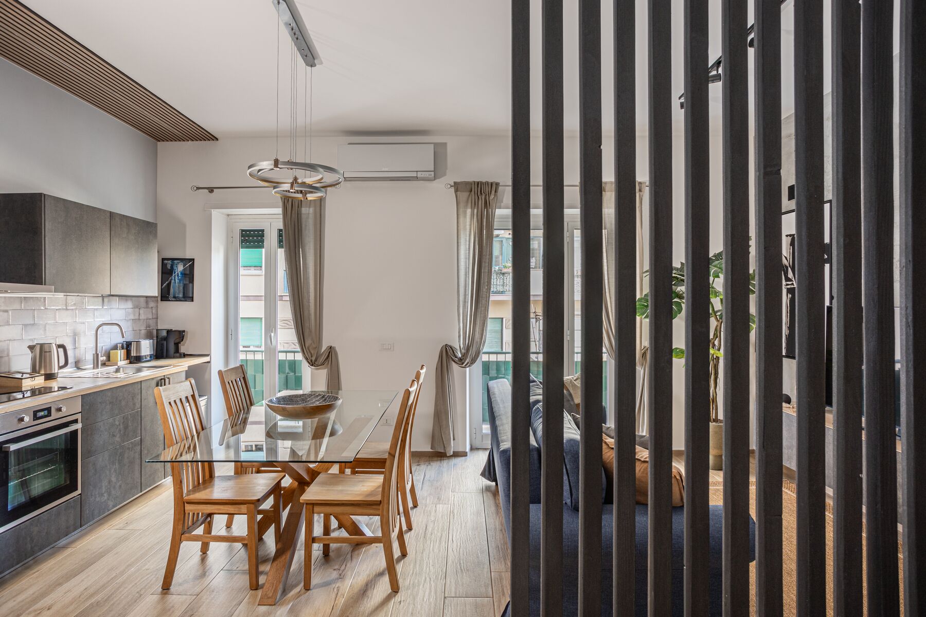 Une cuisine moderne avec un coin repas, comprenant un grand îlot central, des chaises en bois et une table à plateau en verre.