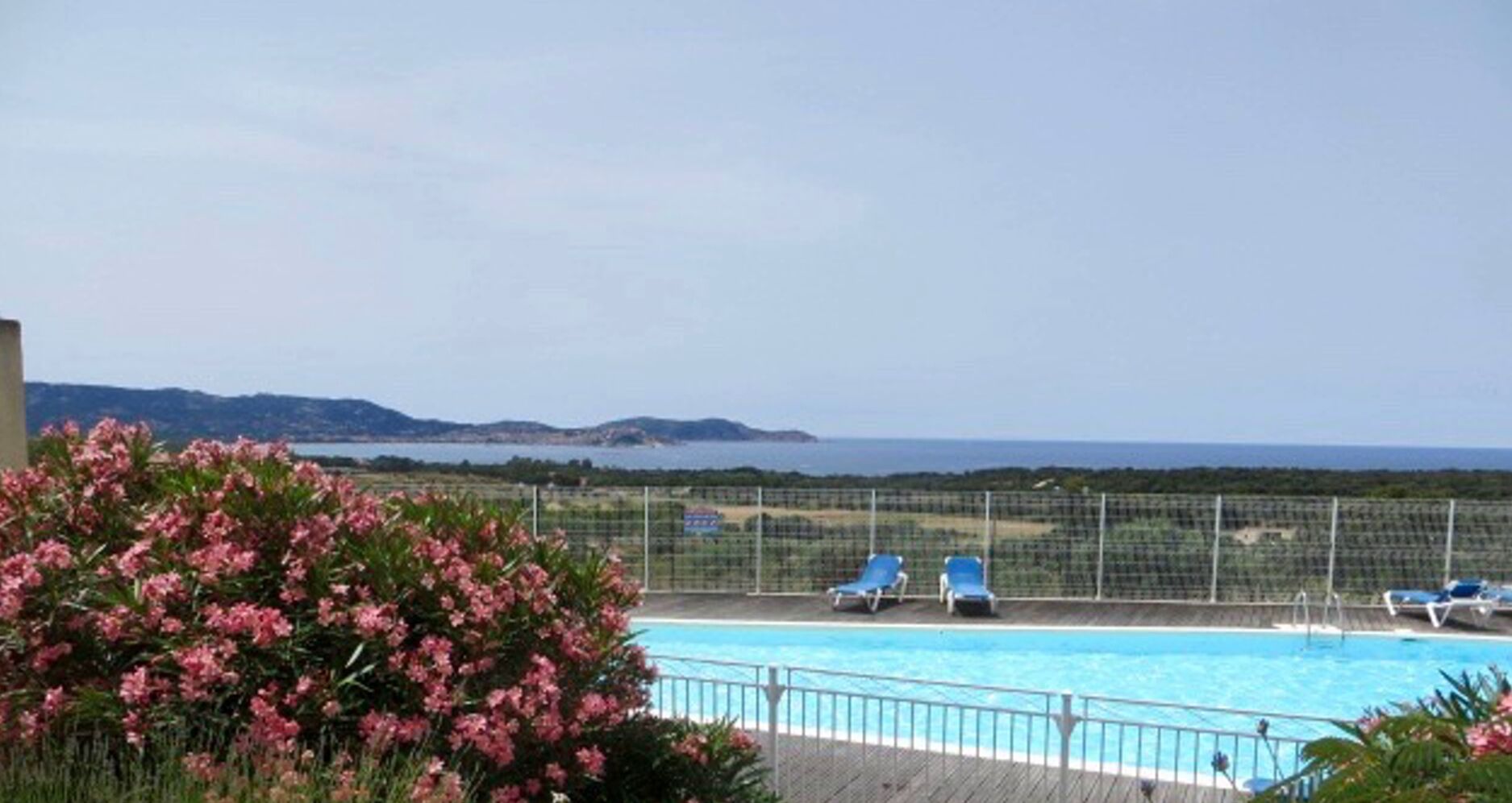 A swimming pool with a view of the sea and hills in the background.