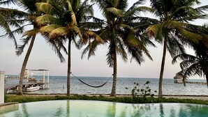 A pool with a view of the sea, surrounded by palm trees and a wooden deck. - Beautiful 5 bedroom beachfront villa with private pool just 2.5 miles from town (San Pedro)