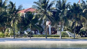 A beachfront property with a red-roofed building, palm trees, and a sandy beach. - Beautiful 5 bedroom beachfront villa with private pool just 2.5 miles from town (San Pedro)