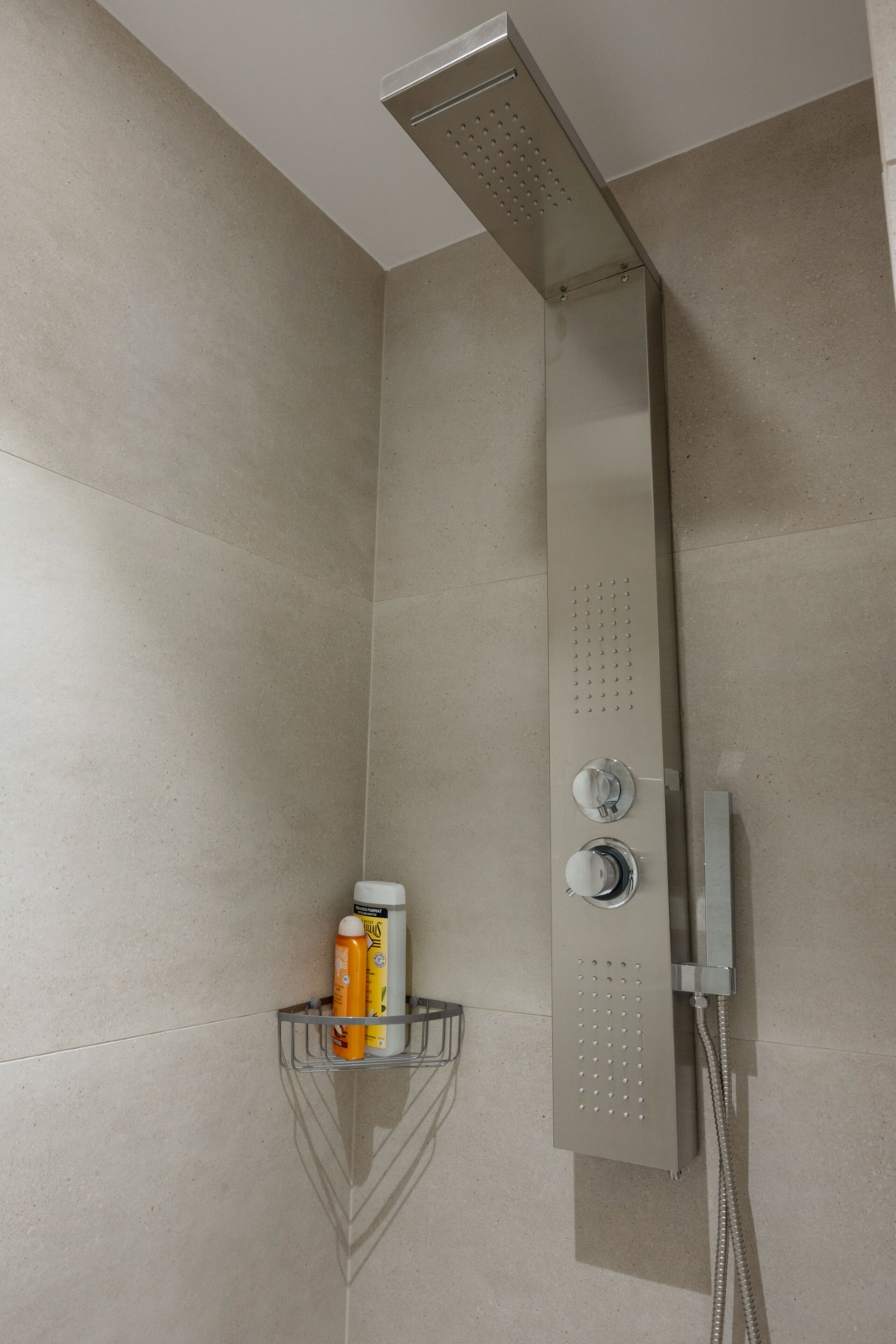 Een douche met een handdouche en een bedieningspaneel aan de muur.