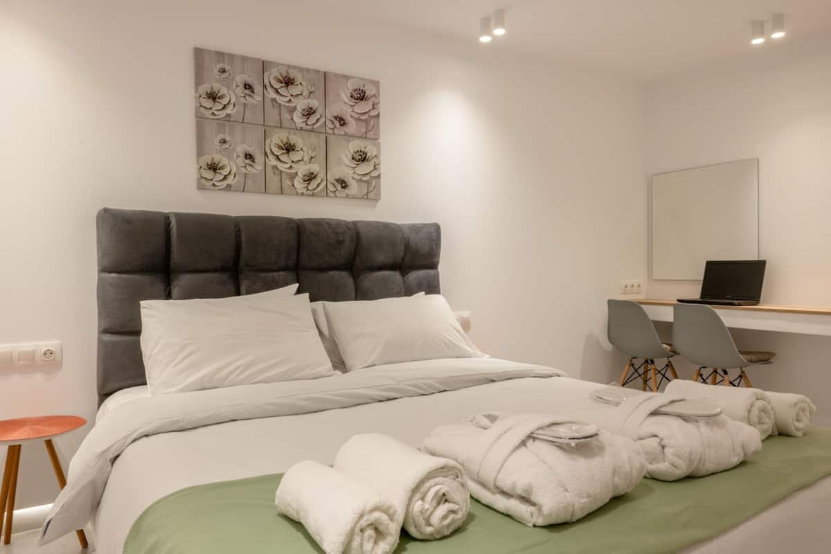 A neatly arranged hotel room with a large bed, a desk with a laptop, and a chair.