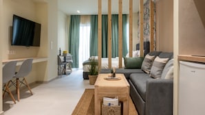 A modern living room with a sofa, a TV, a dining area with chairs, and a kitchen area with a refrigerator. - Heart of Athens Apartments (Athens)