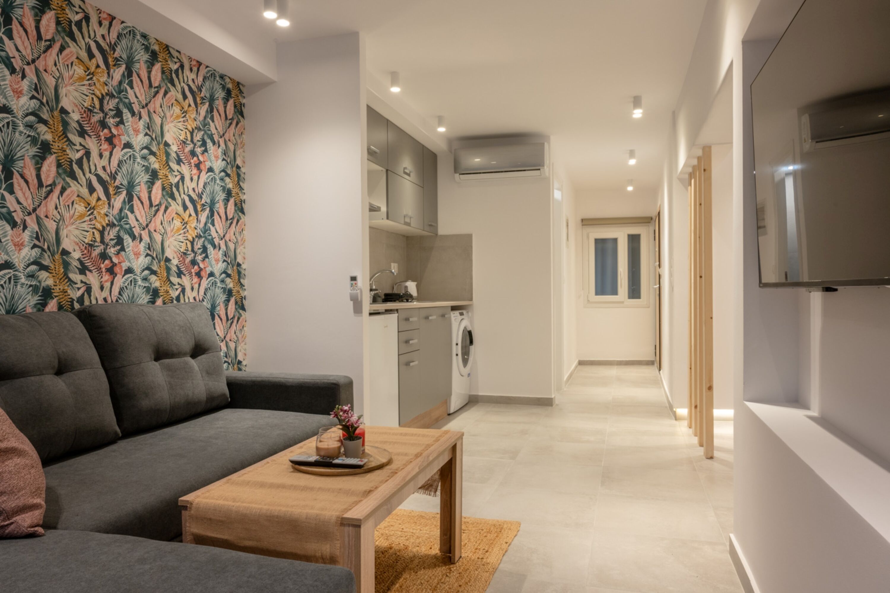 Una sala de estar moderna con sofá, mesa de centro y una cocina al fondo.