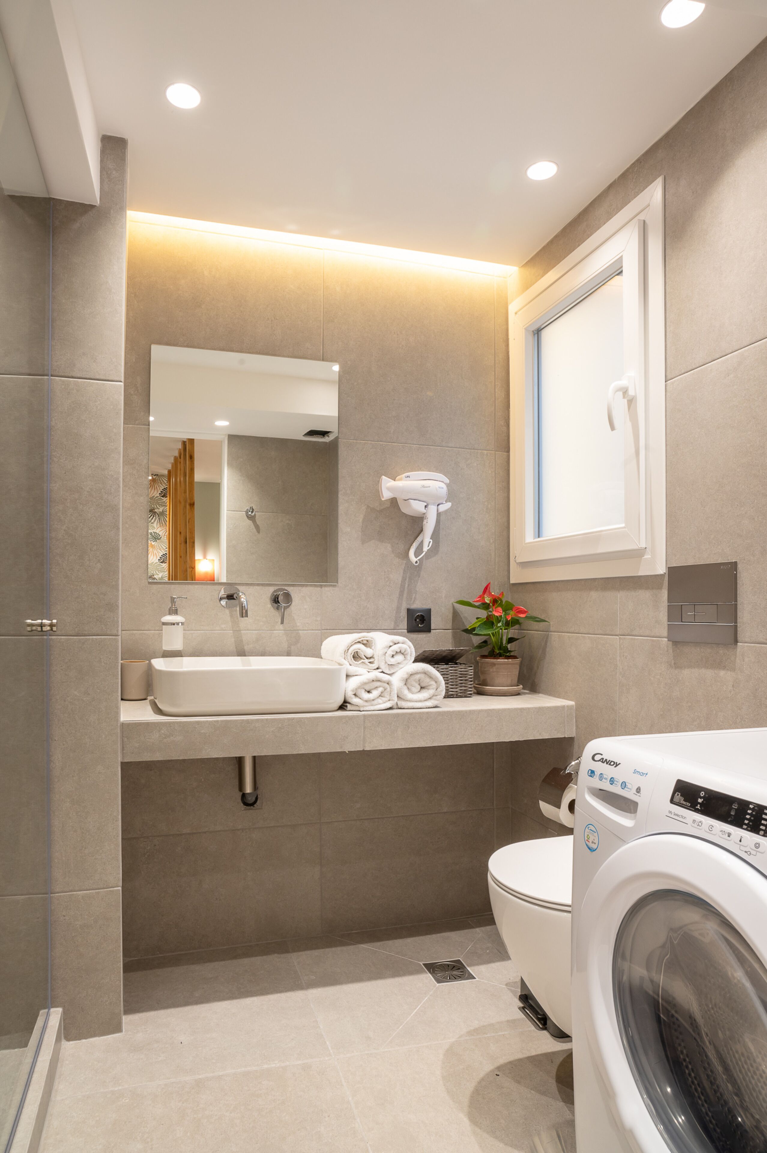 Un bagno moderno con lavandino, specchio, asciugacapelli e lavatrice.