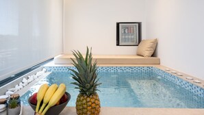 A pool area with a seating area, a bowl of fruit, and a framed picture on the wall. - Heart of Athens Apartments (Athens)