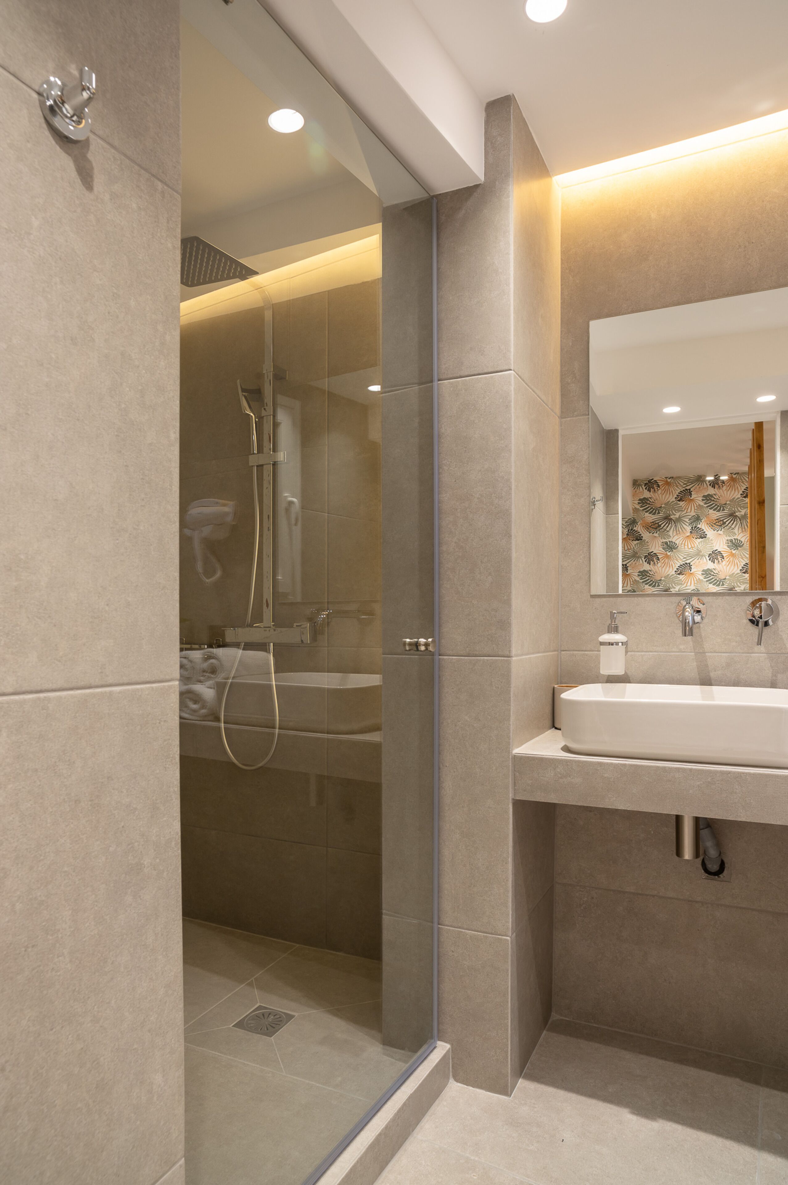 A modern bathroom with a glass-enclosed shower, a sink, and a mirror.