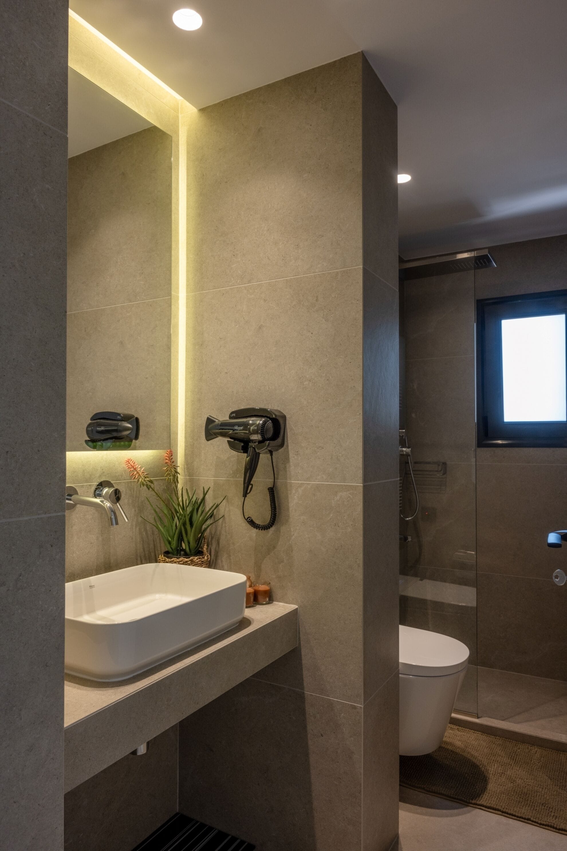 Un bagno moderno con uno specchio grande, un lavandino bianco, un asciugacapelli e una zona doccia.