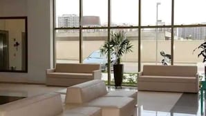 A spacious lobby with large windows, two sofas, and a potted plant.