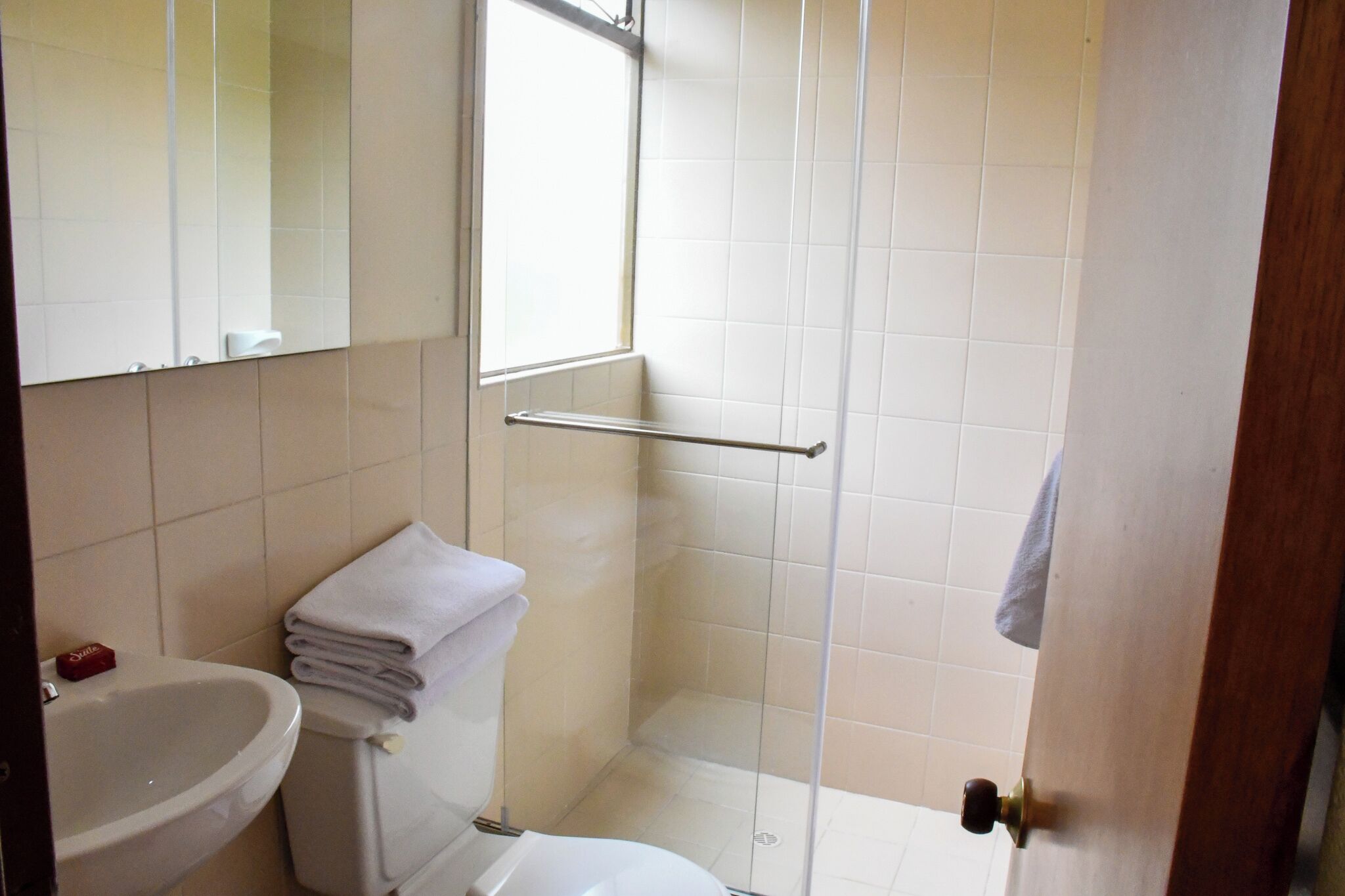 Une salle de bain comprenant des toilettes, un lavabo et une douche séparée par une paroi en verre.
