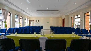 Un salón de conferencias con una larga mesa, sillas azules y un mantel amarillo.