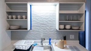 Een keuken met witte kastjes, een gootsteen en een raam met een blauwe handdoek.