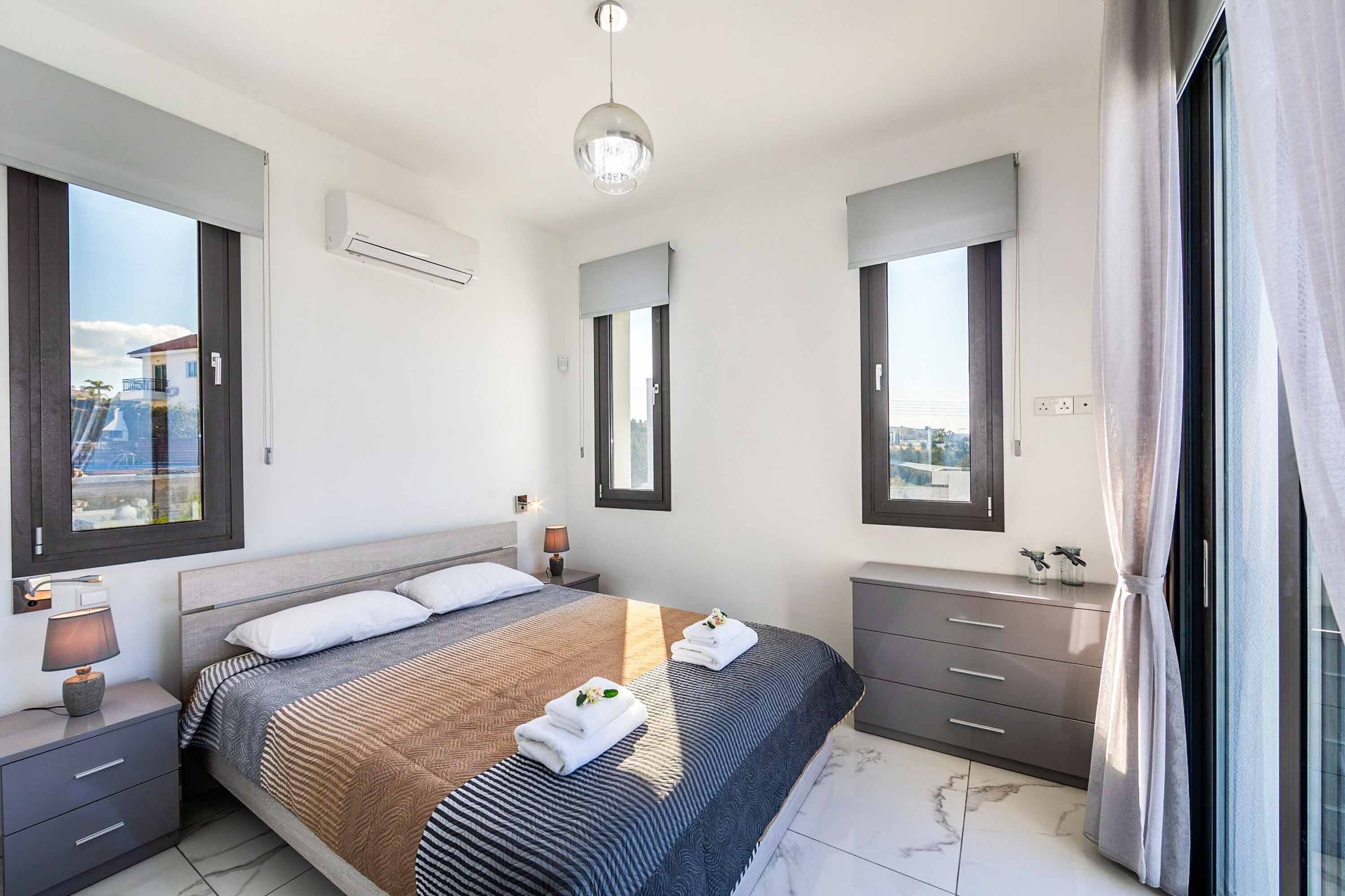 Ein modernes Schlafzimmer mit einem großen Bett, Nachttischen, einem Spiegel und Blick auf die Stadt.