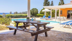 A covered outdoor area with a pool, lounge chairs, and a picnic table. - Villa Theo - Four Bedroom Villa, Sleeps 8 (Peyia)
