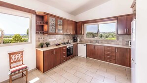 Une cuisine avec des meubles en bois, une cuisinière, un lave-vaisselle et une fenêtre donnant sur un beau paysage.