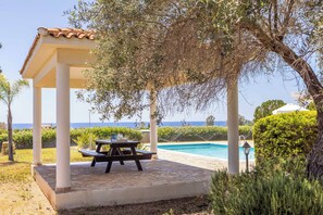 A covered outdoor area with a pool, a picnic table, and a view of the sea. - Villa Theo - Four Bedroom Villa, Sleeps 8 (Peyia)
