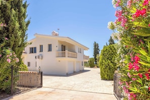 A two-story building with a balcony, a paved driveway, and a gated entrance. - Villa Theo - Four Bedroom Villa, Sleeps 8 (Peyia)