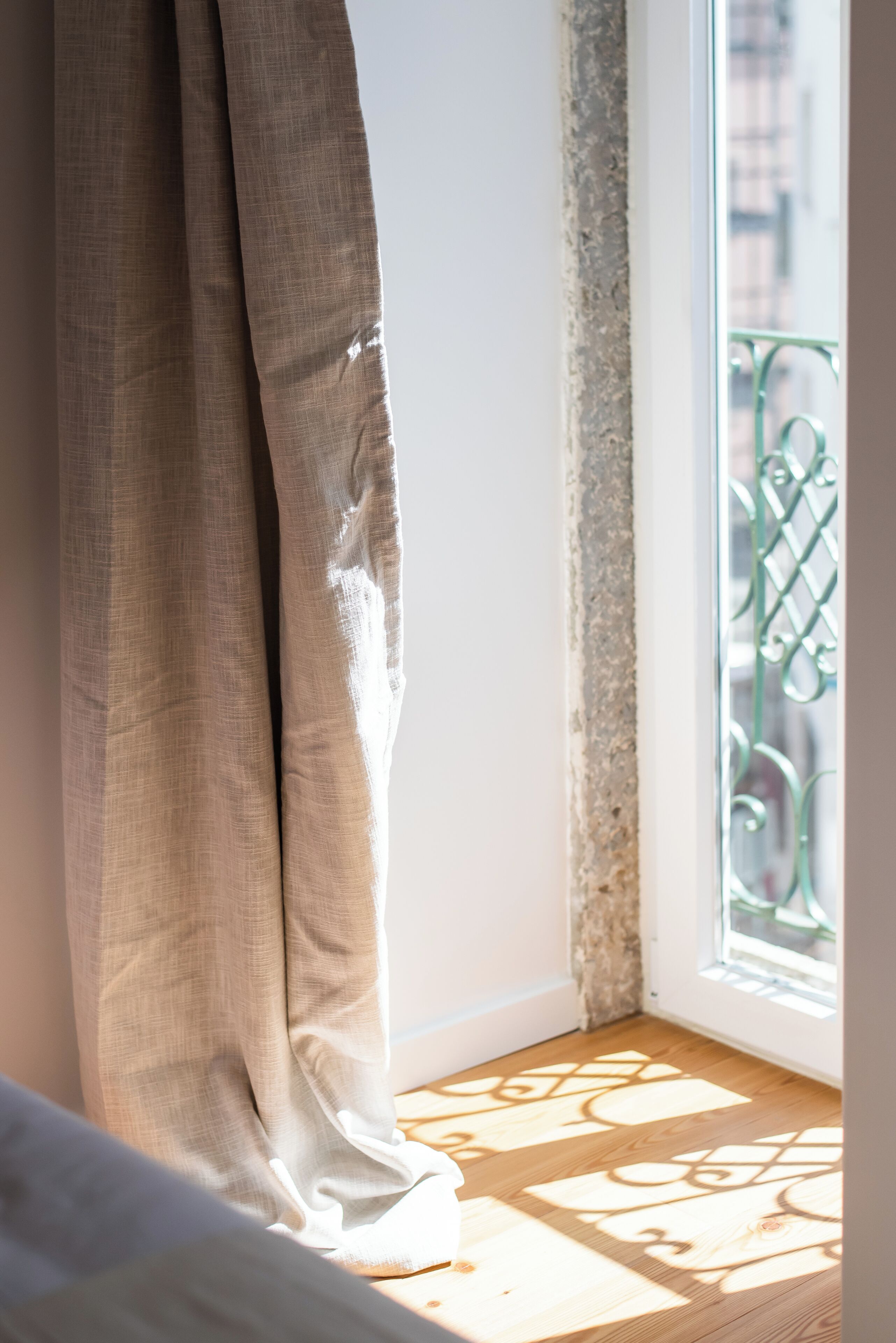 A room with a window, wooden floor, and a curtain.