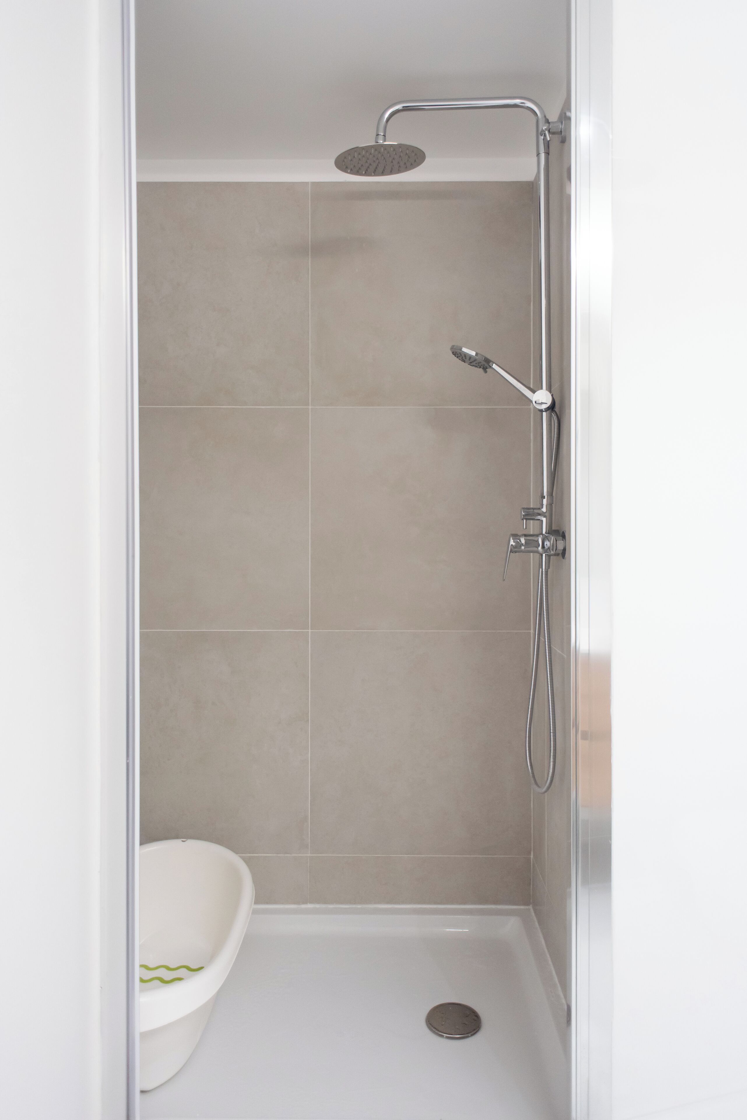 A shower with a handheld showerhead and a wall-mounted faucet.