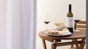 A round wooden table with a bottle of wine, two glasses, a bowl of crackers, and a plate with cheese and meat. - The Haus - Alegria (Lisbon)