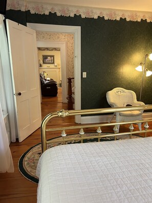 Un dormitorio con cama, una silla, una lámpara y una puerta que da a otra habitación.