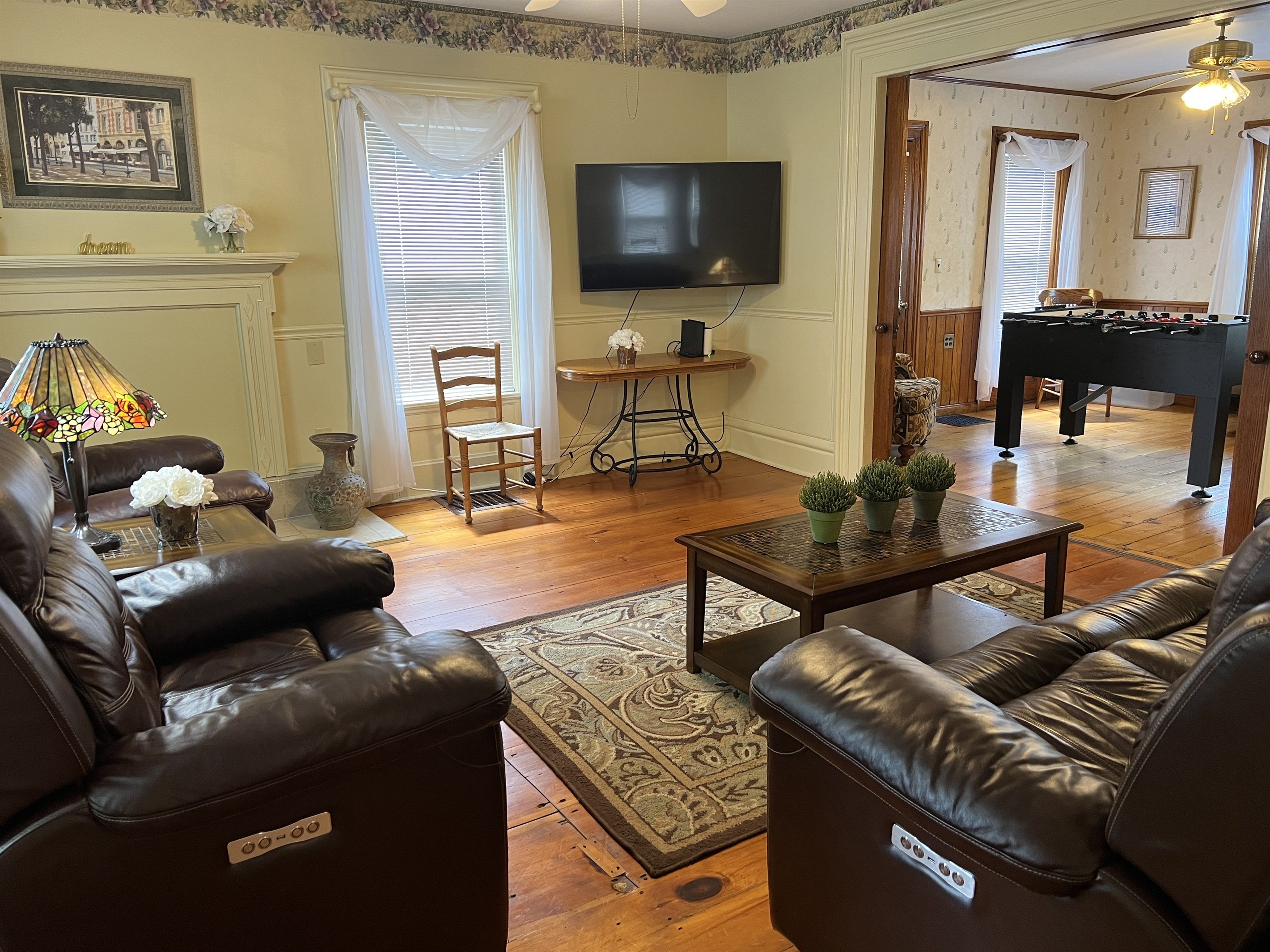 A living room with leather sofas, a television, a fireplace, and a foosball table.