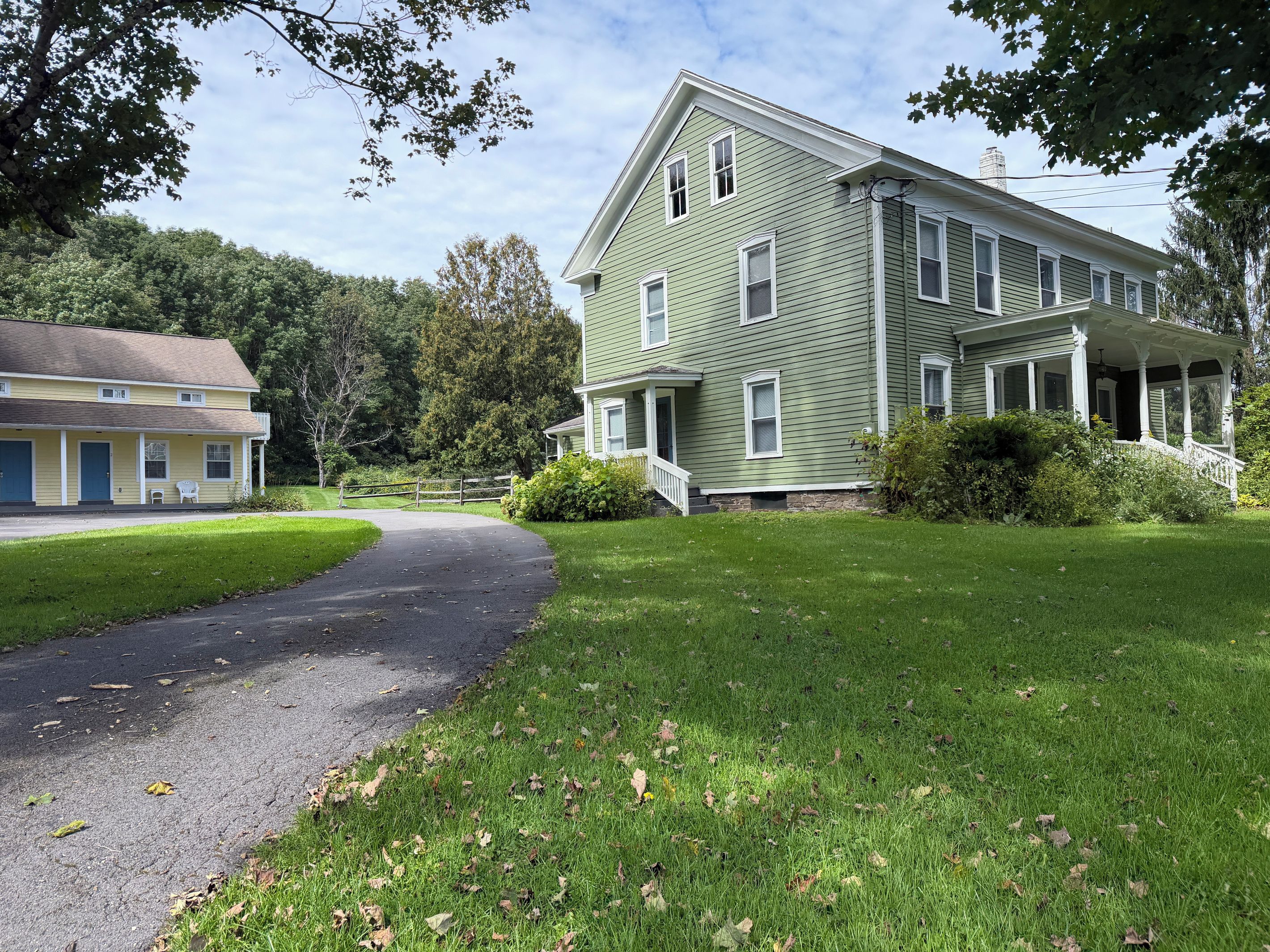 A two-story house with a porch, a driveway, and a well-maintained lawn.