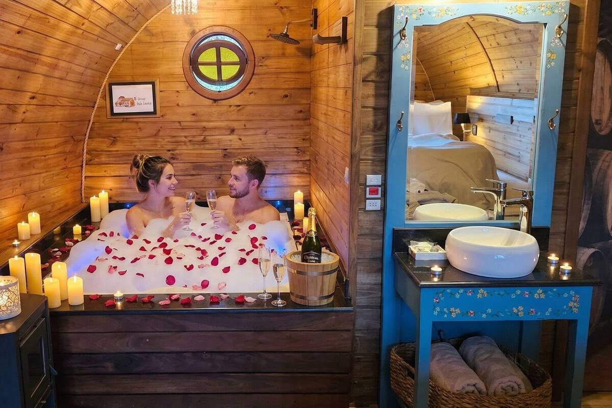 Una habitación estilo cabaña de madera con bañera, velas y una botella de champán.