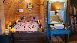 A wooden cabin-style room with a bathtub, candles, and a bottle of champagne. - Pousada Villa Barril (Camanducaia)