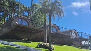 A modern architectural structure with curved balconies and a grassy landscape. - Pousada Villa Barril (Camanducaia)