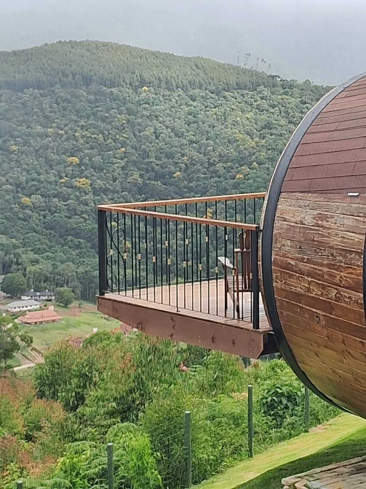 Una estructura cilíndrica de madera con un balcón que se extiende sobre un paisaje verde exuberante.