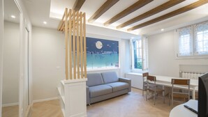 A modern living room with a grey sofa, wooden slats, a dining table with chairs, and a large window with a view of a cityscape. - Ca di Viola e Tobia (Venice)
