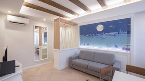 A modern room with a wooden ceiling, a grey sofa, a white desk with a laptop, and a large window with a cityscape mural. - Ca di Viola e Tobia (Venice)