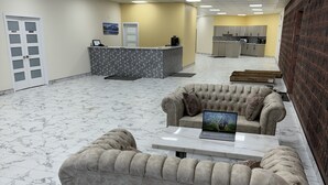 Un vestíbulo amplio con mostrador de recepción, zona de cocina y rincones de estar.