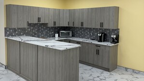 Una cocina con gabinetes grises, encimera de mármol y un microondas.